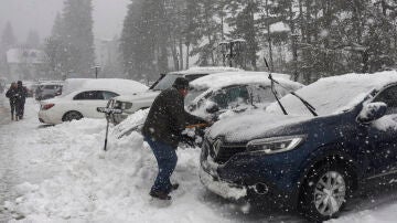 Turistas y habitantes de Canfranc quitan la nieve de sus coches con palas debido a la nieve caída.