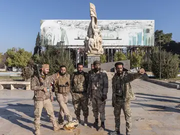Miembros de grupos armados insurgentes posan tras el derribo de una estatua del expresidente Hafez al Assad Miembros de grupos armados insurgentes posan tras el derribo de una estatua del expresidente Hafez al Assad