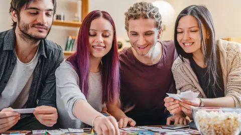 Un grupo de amigos se divierte con un juego de mesa Un grupo de amigos se divierte con un juego de mesa