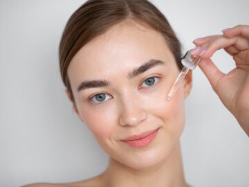 Primer plano del rostro de una mujer aplic&aacute;ndose s&eacute;rum