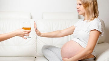 Una mujer embarazada rechaza una copa de cerveza con alcohol.