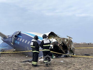 Miembros de los servicios de emergencias examinan los restos del avión 