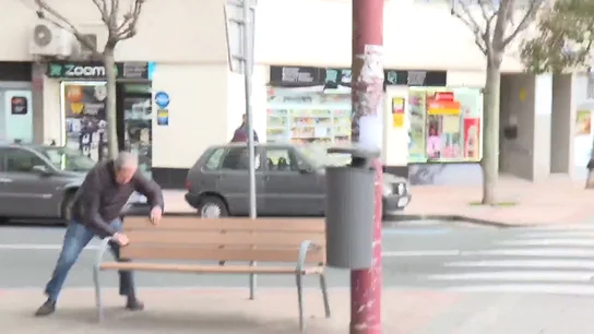 Hombre sujetándose a un banco por el viento Hombre sujetándose a un banco por el viento