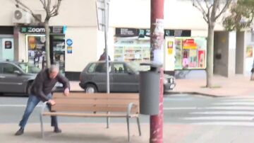 Hombre sujetándose a un banco por el viento