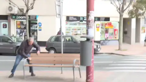 Hombre sujetándose a un banco por el viento Hombre sujetándose a un banco por el viento