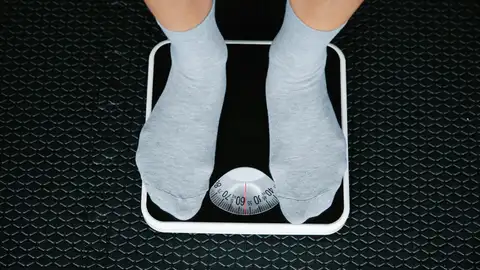 Persona pesándose en una báscula Persona pesándose en una báscula