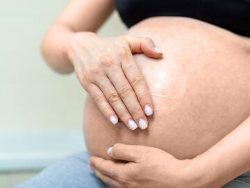 Mujer embarazada con crema en la barriga 