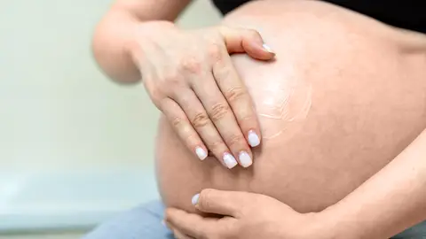 Mujer embarazada con crema en la barriga Mujer embarazada con crema en la barriga