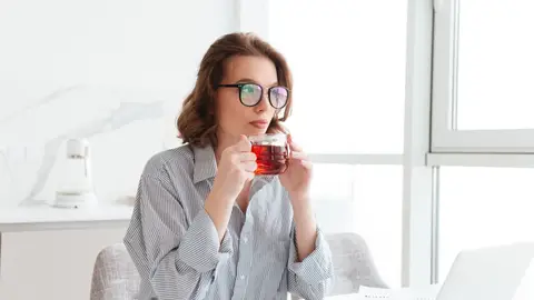 Una mujer toma té mientras trabaja Una mujer toma té mientras trabaja