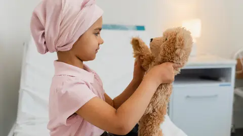 Una niña en el hospital juega con su peluche Una niña en el hospital juega con su peluche