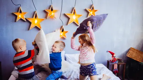 Imagen de archivo de unos niños haciendo guerra de almohadas Imagen de archivo de unos niños haciendo guerra de almohadas