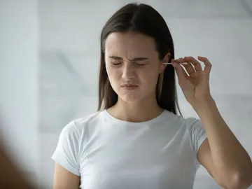 Cara de dolor al limpiarse el oído con un bastoncillo Cara de dolor al limpiarse el oído con un bastoncillo