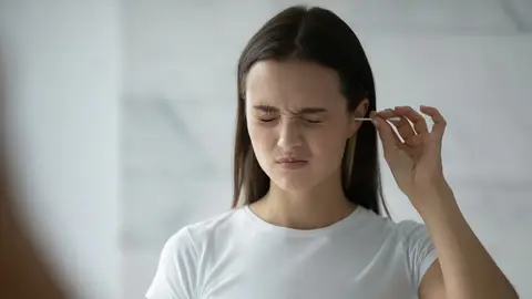 Cara de dolor al limpiarse el oído con un bastoncillo Cara de dolor al limpiarse el oído con un bastoncillo