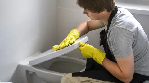Hombre limpiando el váter Hombre limpiando el váter