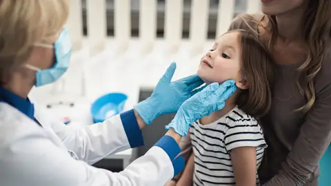 Doctora palpando las amígdalas a una niña Doctora palpando las amígdalas a una niña