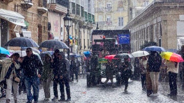 Asistentes al público e integrantes de las agrupaciones se resguardan de la lluvia este domingo en Cádiz