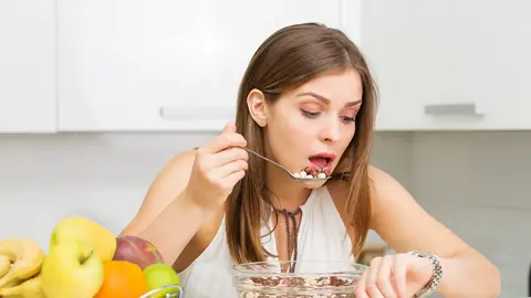 Una mujer comiendo mientras mira el reloj Una mujer comiendo mientras mira el reloj