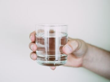 Imagen de archivo de una mano sosteniendo un vaso de agua.