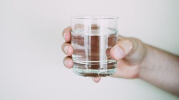 Imagen de archivo de una mano sosteniendo un vaso de agua.