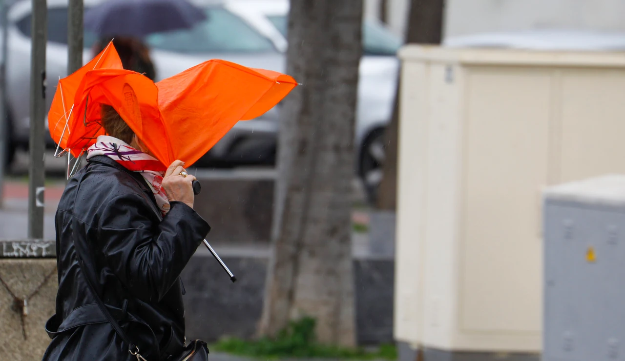 Una mujer trata de protegerse con un paraguas del temporal de viento y lluvia