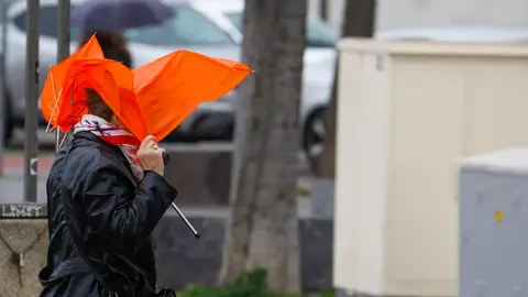 Una mujer trata de protegerse con un paraguas del temporal de viento y lluvia Una mujer trata de protegerse con un paraguas del temporal de viento y lluvia