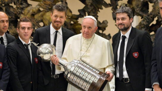 El papa Francisco con el trofeo de la Copa Libertadores, rodeado de miembros del equipo San Lorenzo, en 2014