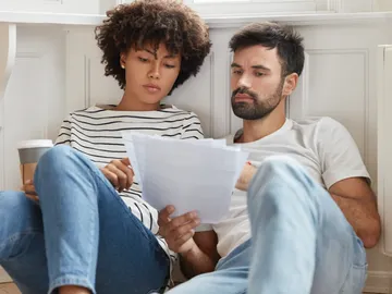 Una pareja leyendo juntos sus anotaciones Una pareja leyendo juntos sus anotaciones