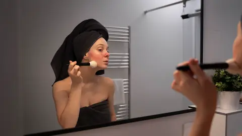 Mujer con rosácea se aplica un cosmético Mujer con rosácea se aplica un cosmético