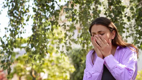 Mujer estornudando por la alergia Mujer estornudando por la alergia