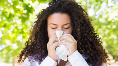 Mujer con alergia sonándose Mujer con alergia sonándose