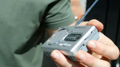 Una persona escucha una radio por pilas Una persona escucha una radio por pilas