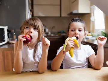 Dos niñas comiendo fruta Dos niñas comiendo fruta