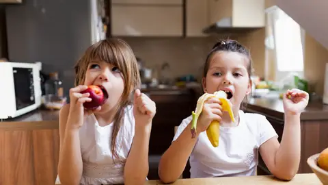 Dos niñas comiendo fruta Dos niñas comiendo fruta
