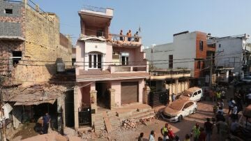 Residentes indios inspeccionan una casa dañada tras un bombardeo transfronterizo desde Pakistán