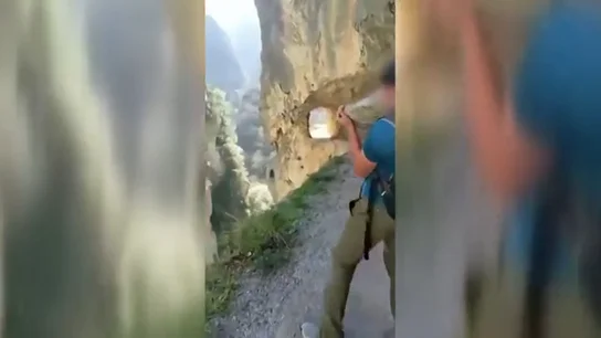 Un joven tira una piedra por un barranco en los Picos de Europa Un joven tira una piedra por un barranco en los Picos de Europa