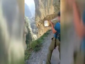 Un joven tira una piedra por un barranco en los Picos de Europa
