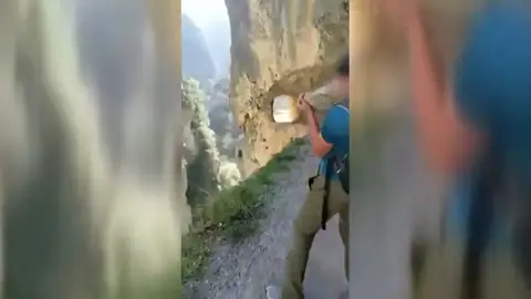 Un joven tira una piedra por un barranco en los Picos de Europa Un joven tira una piedra por un barranco en los Picos de Europa