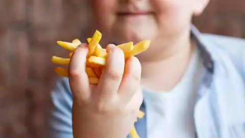 Un niño comiendo patatas fritas Obesidad infantil
