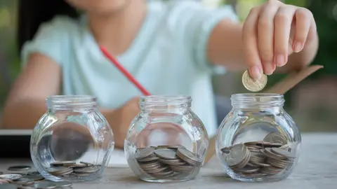 Una niña ahorrando monedas Una niña ahorrando monedas