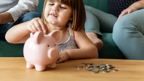 Una niña guardando dinero el la hucha Una niña guardando dinero el la hucha