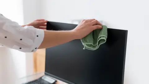 Persona limpiando la pantalla del ordenador Persona limpiando la pantalla del ordenador