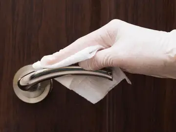 Persona limpiando la manilla de una puerta Persona limpiando la manilla de una puerta