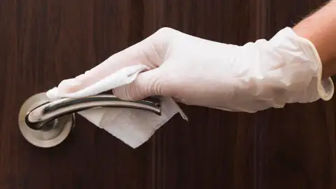 Persona limpiando la manilla de una puerta Persona limpiando la manilla de una puerta