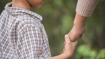 Niño dando la mano a un adulto