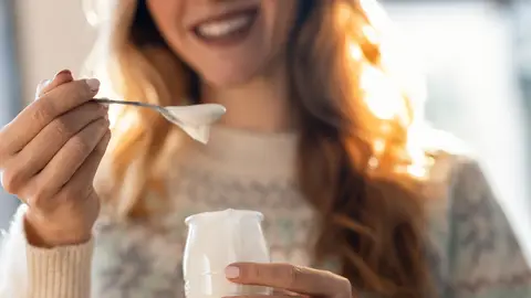 Una persona comiéndose un yogur Una persona comiéndose un yogur