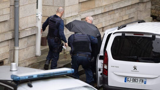 El cirujano jubilado Joel Le Scouarnec llega a su juicio oculto bajo un paraguas acusado de agredir o violar a 299 pacientes en el Tribunal Penal de Vannes.