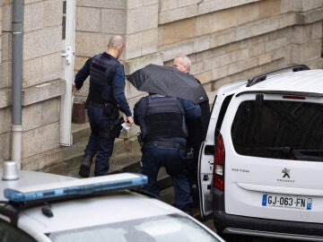 El cirujano jubilado Joel Le Scouarnec llega a su juicio oculto bajo un paraguas acusado de agredir o violar a 299 pacientes en el Tribunal Penal de Vannes.