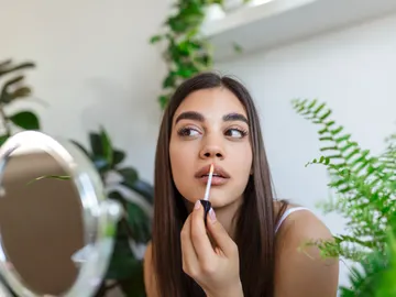 Mujer aplicándose gloss labial Mujer aplicándose gloss labial