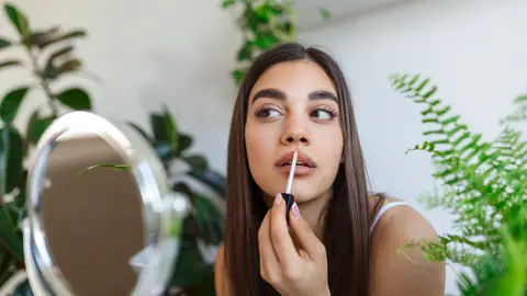 Mujer aplicándose gloss labial Mujer aplicándose gloss labial