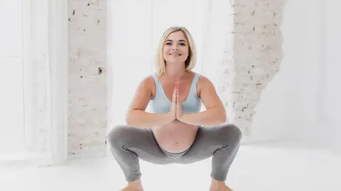 Embarazada haciendo una sentadilla Embarazada haciendo una sentadilla